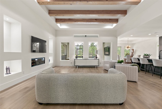 living room featuring a notable chandelier, beam ceiling, and light hardwood / wood-style flooring