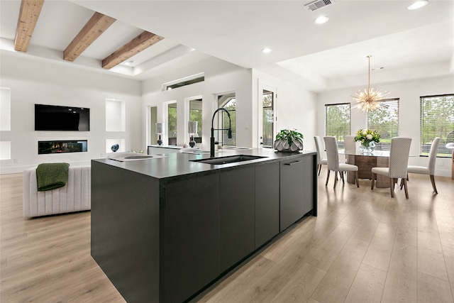 kitchen with pendant lighting, a spacious island, sink, and light hardwood / wood-style flooring