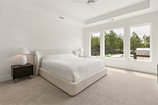 carpeted bedroom with a tray ceiling and ceiling fan