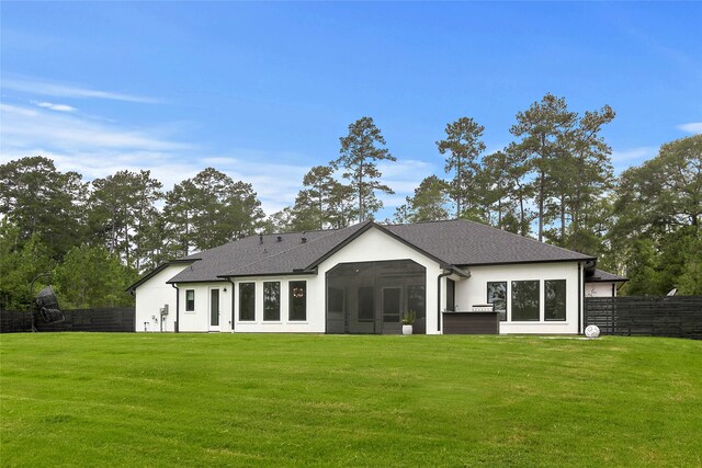 rear view of house featuring a lawn and a sunroom