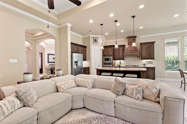 living room featuring ceiling fan, sink, and crown molding