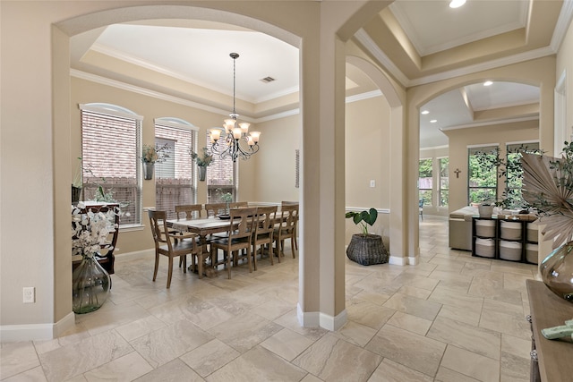 dining area with a raised ceiling, crown molding, and an inviting chandelier