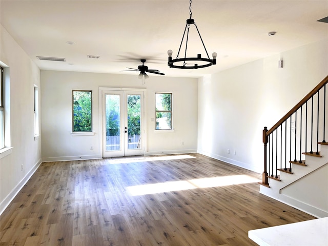 unfurnished living room with french doors, ceiling fan with notable chandelier, and hardwood / wood-style flooring