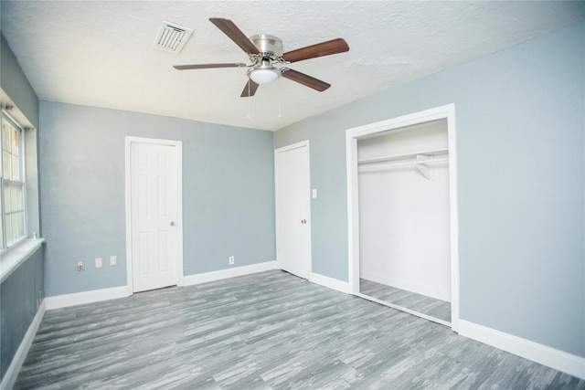 unfurnished bedroom featuring a textured ceiling, wood-type flooring, and ceiling fan