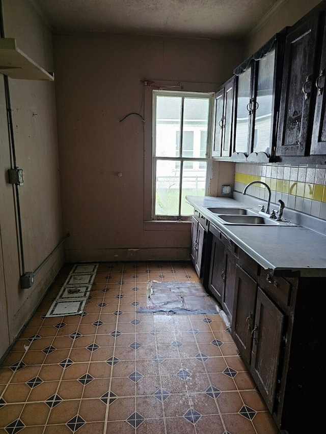 kitchen featuring dark brown cabinetry, sink, and backsplash