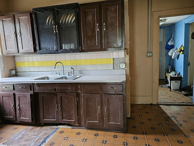 kitchen with dark brown cabinetry, sink, and tasteful backsplash