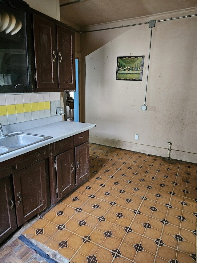 kitchen featuring sink, decorative backsplash, dark brown cabinetry, and crown molding