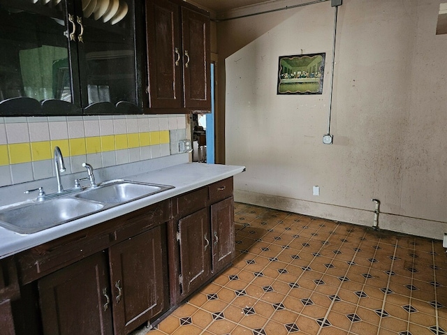 kitchen with decorative backsplash, dark brown cabinetry, and sink