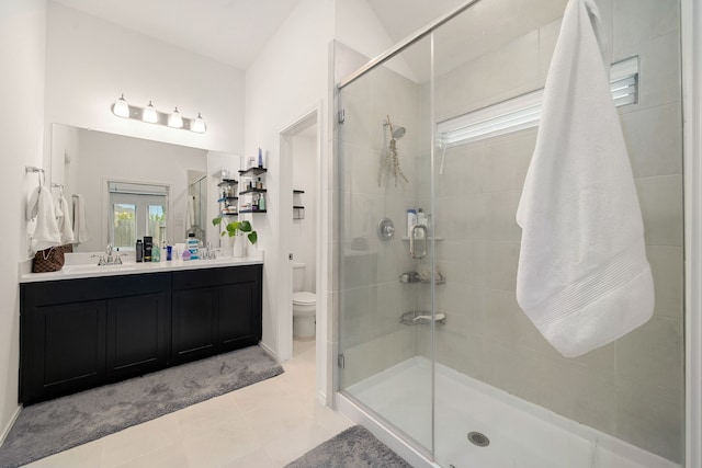 bathroom featuring tile patterned flooring, vanity, toilet, and walk in shower