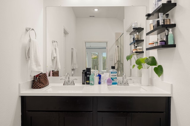 bathroom featuring a shower with door and vanity