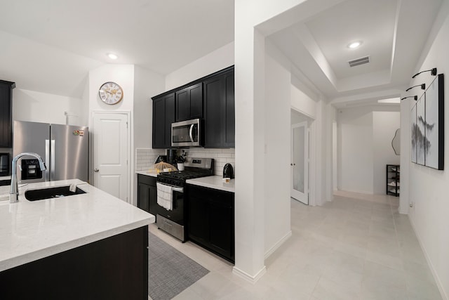 kitchen featuring sink, backsplash, stainless steel appliances, and a barn door