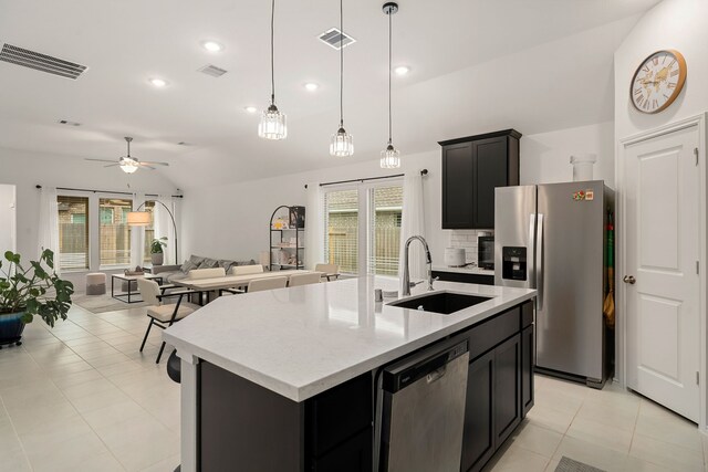 kitchen featuring backsplash, stainless steel appliances, ceiling fan, sink, and an island with sink