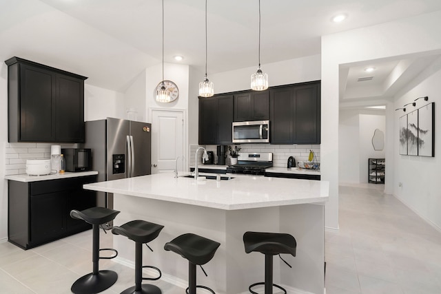 kitchen with sink, a center island with sink, stainless steel appliances, and decorative light fixtures