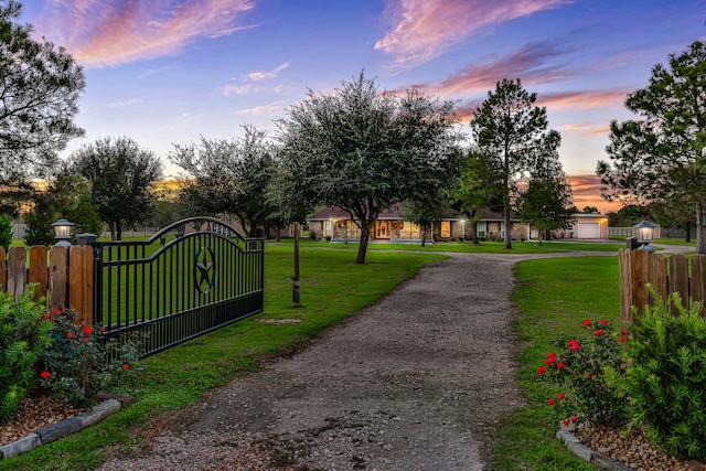 gate at dusk featuring a lawn