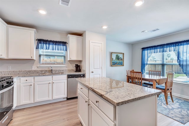 kitchen featuring sink, appliances with stainless steel finishes, light hardwood / wood-style flooring, a center island, and white cabinets