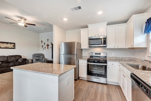 kitchen featuring appliances with stainless steel finishes, sink, light hardwood / wood-style floors, and white cabinets