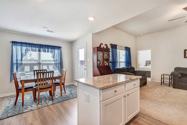 kitchen featuring white cabinetry, a wealth of natural light, light hardwood / wood-style floors, and light stone counters