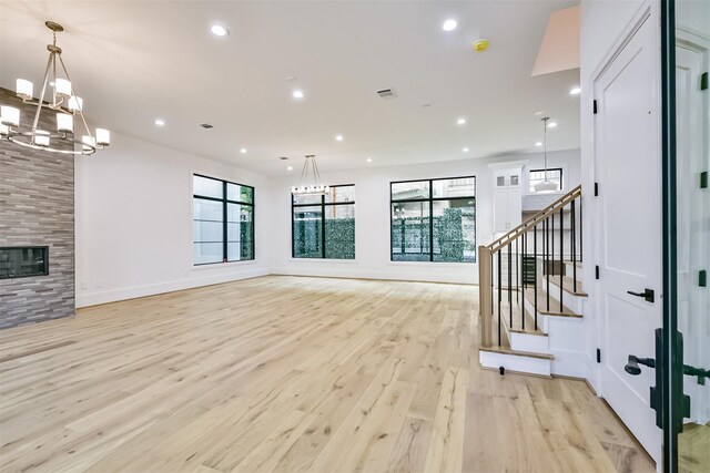 living room featuring a large fireplace, light hardwood / wood-style flooring, and an inviting chandelier