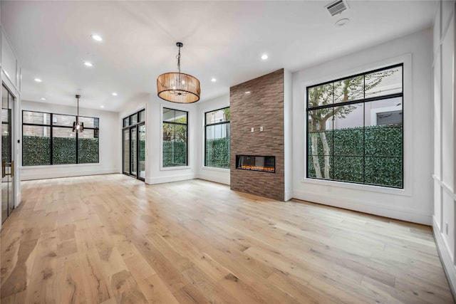 unfurnished living room featuring a fireplace, light hardwood / wood-style flooring, and a notable chandelier