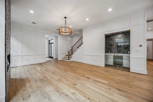 unfurnished living room featuring an inviting chandelier and light wood-type flooring