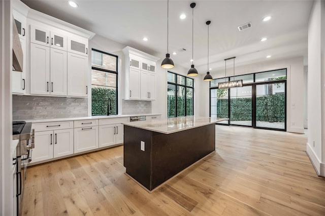 kitchen with white cabinetry, light wood-type flooring, a kitchen island, and decorative light fixtures