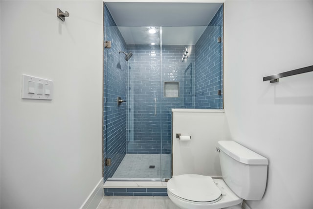 bathroom featuring toilet, an enclosed shower, and tile patterned floors