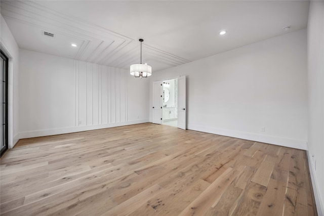 spare room with light wood-type flooring and a chandelier