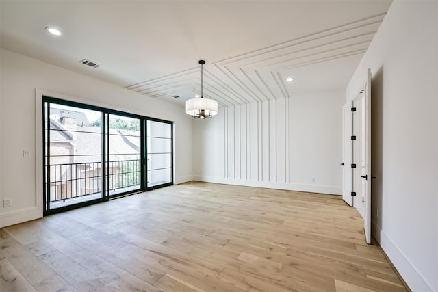 empty room featuring light wood-type flooring and a chandelier