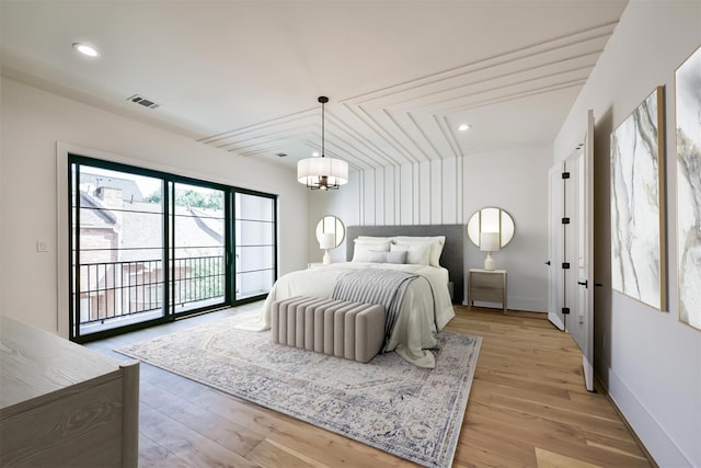 bedroom with access to exterior, light wood-type flooring, and a notable chandelier