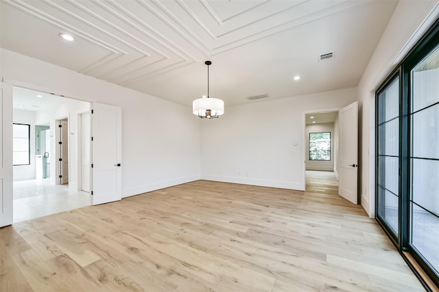 spare room with light wood-type flooring and an inviting chandelier