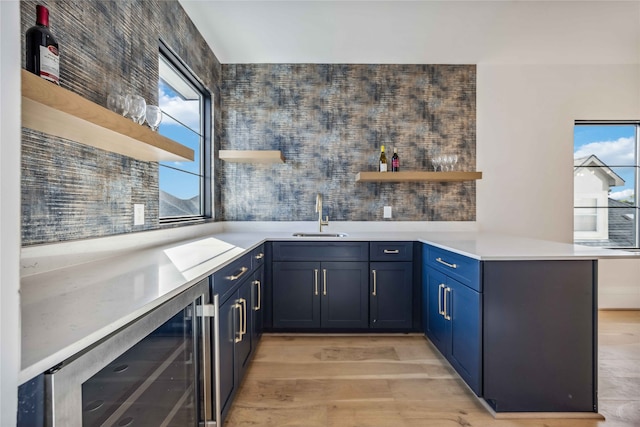 kitchen featuring light hardwood / wood-style floors, sink, wine cooler, kitchen peninsula, and blue cabinetry