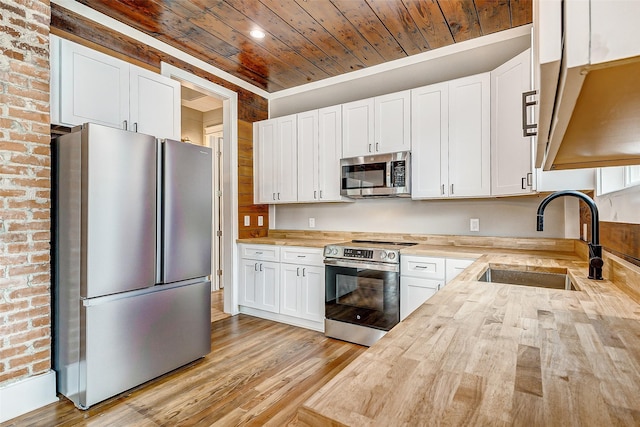 1324 Ursuline St, Galveston, TX 77550 - kitchen with appliances with stainless steel finishes, wooden ceiling, wooden counters, a sink, and light wood finished floors