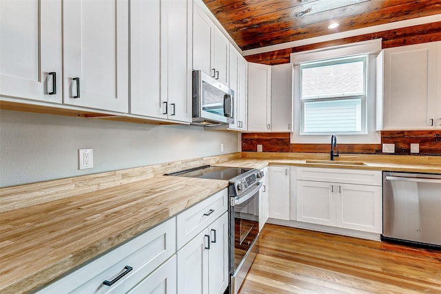 1324 Ursuline St, Galveston, TX 77550 - kitchen with appliances with stainless steel finishes, a sink, white cabinets, wooden ceiling, and light wood finished floors