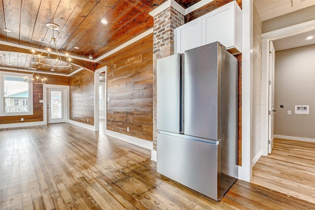 1324 Ursuline St, Galveston, TX 77550 - kitchen featuring freestanding refrigerator, wooden ceiling, wood walls, light wood-type flooring, and white cabinets