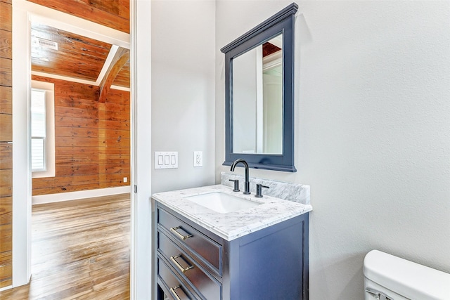 1324 Ursuline St, Galveston, TX 77550 - bathroom featuring wood walls, wood ceiling with exposed beams, toilet, vanity, and wood finished floors