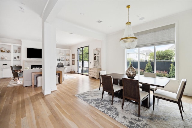 dining room featuring light hardwood / wood-style floors, built in features, and a notable chandelier