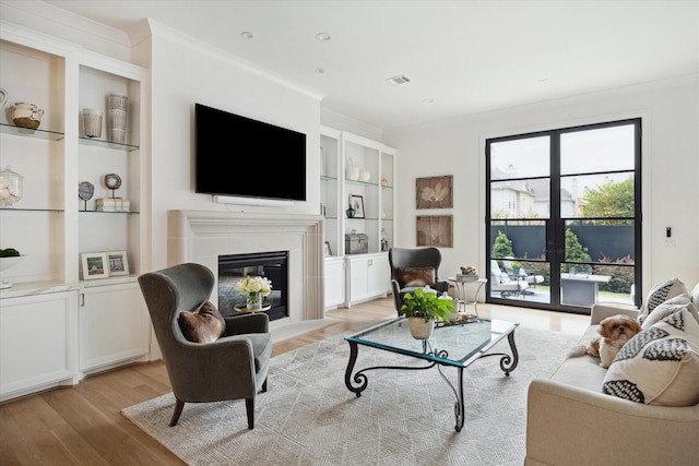 living room featuring light hardwood / wood-style floors, built in features, and ornamental molding