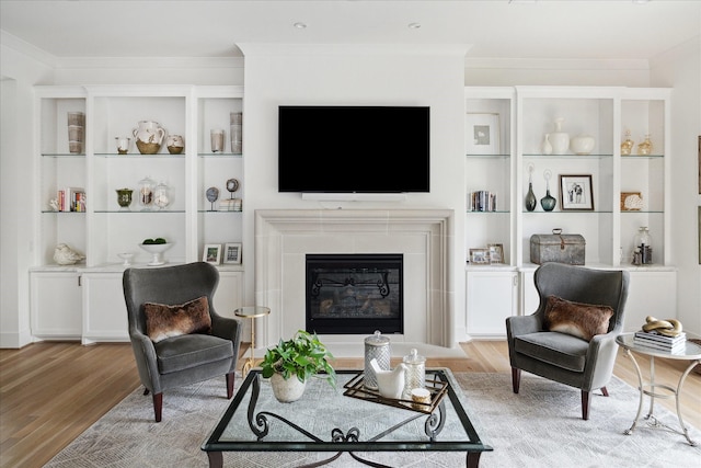 living room with light hardwood / wood-style floors, ornamental molding, and built in features