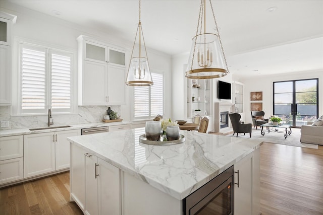 kitchen featuring backsplash, white cabinetry, built in microwave, and sink