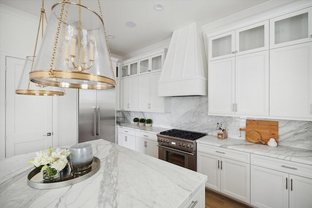 kitchen with white cabinets, light stone countertops, custom range hood, and stainless steel stove