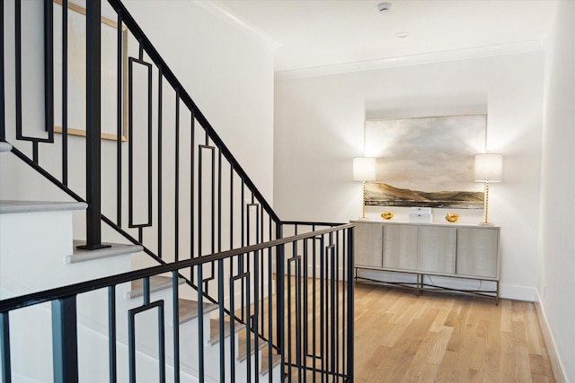 stairway featuring hardwood / wood-style floors, baseboard heating, and ornamental molding