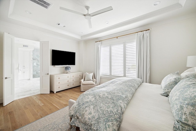 bedroom featuring ceiling fan, a raised ceiling, and light wood-type flooring