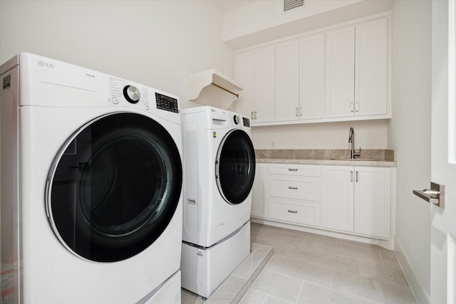 laundry room featuring light tile patterned flooring, sink, cabinets, and washing machine and clothes dryer