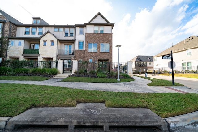 townhome / multi-family property with a balcony and a front yard