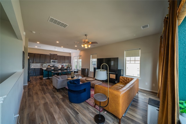 living room with dark wood-type flooring and ceiling fan