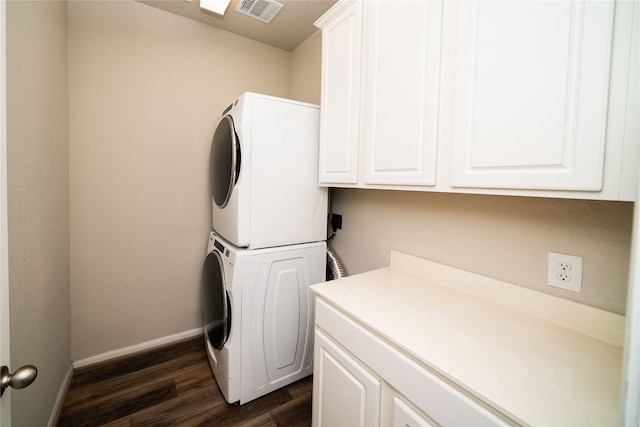 washroom featuring cabinets, dark hardwood / wood-style floors, and stacked washer and clothes dryer