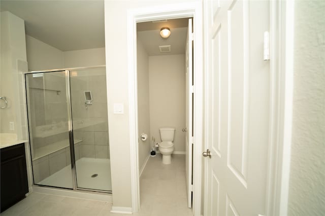 bathroom featuring toilet, vanity, tile patterned floors, and a shower with shower door