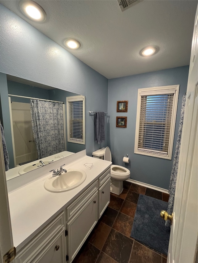 bathroom with curtained shower, vanity, a textured ceiling, and toilet