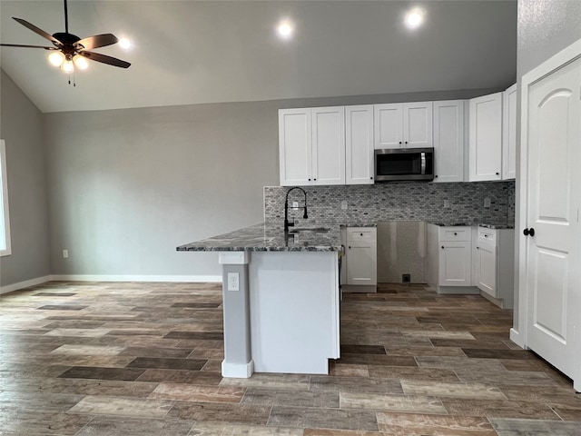 kitchen featuring white cabinets, lofted ceiling, dark stone countertops, and dark hardwood / wood-style flooring