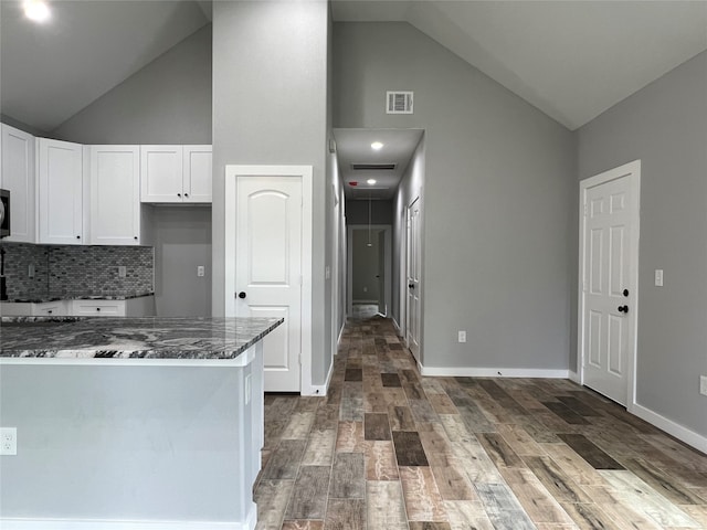 kitchen featuring dark hardwood / wood-style flooring, dark stone countertops, white cabinetry, and high vaulted ceiling